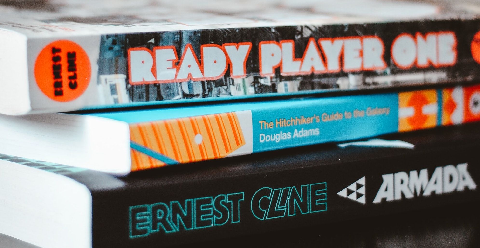 Stack of sci-fi books (Ready Player One, Hitchhikers Guide to the Galaxy, and Armada)